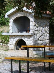 un horno de piedra con un banco delante de él en Wohnung in Barbat mit Terrasse und Grill en Barbat na Rabu