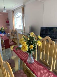 a dining room with a table with a vase of yellow flowers at Apartamento central em João Monlevade in João Monlevade