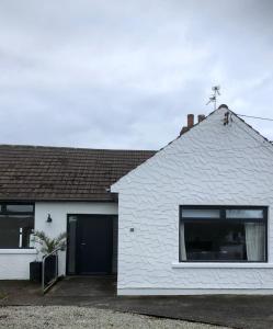 a white house with a black door and a window at The Bunga, Portrush in Portrush
