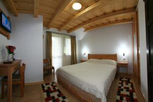 a bedroom with a bed and a table and a window at Pensiunea Casa Elvira in Vama