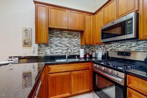 cocina con armarios de madera, fogones y microondas en La Quinta Leisure, en La Quinta