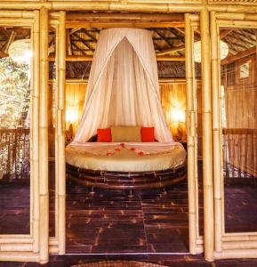 a bed in a room with a canopy at Eco Bamboo Island Bali - Bamboo House #4 in Selat