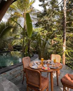 a wooden table with plates of food on a patio at Eco Bamboo Island Bali - Bamboo House #4 in Selat