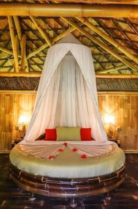 a bed with a white canopy in a room at Eco Bamboo Island Bali - Bamboo House #4 in Selat