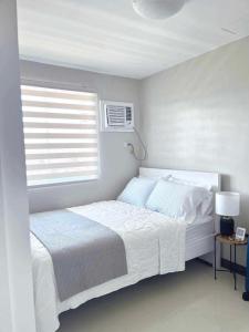 a white bedroom with a bed and a window at Palawan Paradise Condotel 6F in Puerto Princesa City