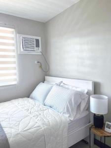1 dormitorio con 1 cama blanca y aire acondicionado en Palawan Paradise Condotel 6F en Puerto Princesa