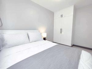 a white bedroom with a large bed and a white cabinet at Palawan Paradise Condotel 6F in Puerto Princesa City