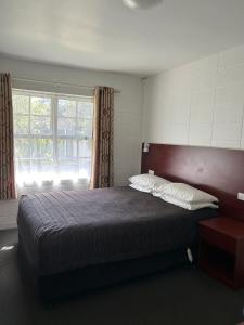 漢密爾頓的住宿－都鐸汽車旅館，一间卧室设有一张大床和一个窗户。