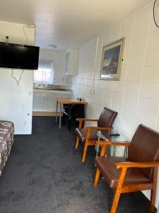 a room with chairs and a table and a kitchen at Tudor Motor Lodge in Hamilton