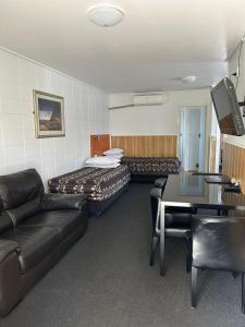 une chambre d'hôtel avec un canapé et une table dans l'établissement Tudor Motor Lodge, à Hamilton