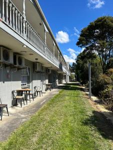 un bâtiment vide avec des tables et des chaises dans l'herbe dans l'établissement Tudor Motor Lodge, à Hamilton