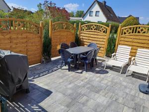 un patio con mesa, sillas y vallas de madera en Ferienhaus Kallies - Dat grote Huus en Bornhöved