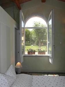 een gewelfd raam in een slaapkamer met een bed en een raam met planten bij Wohnung in Cascina mit Privatem Garten in Cascina