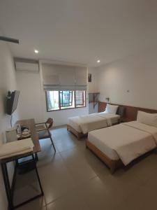 Djajanti House في سيمارانغ: غرفة فندقية بسريرين وطاولة وغرفة بسريرين