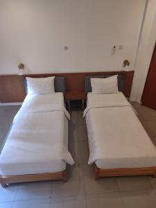 duas camas num quarto de hotel com lençóis brancos em Djajanti House em Semarang