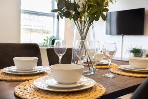 a table with plates and glasses and a vase with flowers at Cosy Central 2 Bedroom - Near Brighton Beach & Shops! in Brighton & Hove