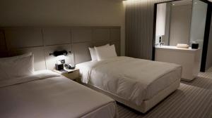 a hotel room with two beds and a sink at Greet Inn in Kaohsiung