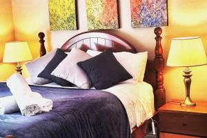 - une chambre dotée d'un lit avec des oreillers et des peintures murales dans l'établissement Poolway Cottage Hepburn Springs, à Hepburn Springs