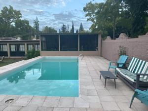 a swimming pool with two blue chairs and a bench at Besares 722 in Chacras de Coria