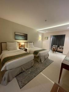 a hotel room with two beds and a living room at Best Western Plus Buraidah in Buraydah