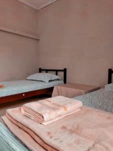 three beds in a room with towels on them at Brussels Homestay Kost in Balige
