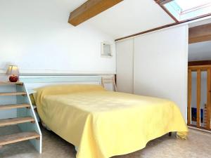 Un dormitorio con una cama amarilla y una escalera en Maison Bormes-les-Mimosas, 2 pièces, 4 personnes - FR-1-251-649, en Bormes-les-Mimosas