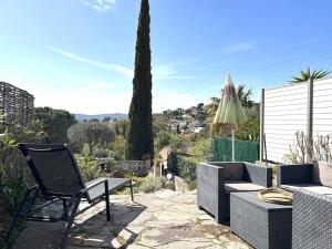 un patio con sillas, una mesa y una sombrilla en Maison Bormes-les-Mimosas, 2 pièces, 4 personnes - FR-1-251-649, en Bormes-les-Mimosas