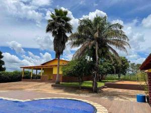 a house with two palm trees and a swimming pool at Recanto Minas a Goiás in Ceres