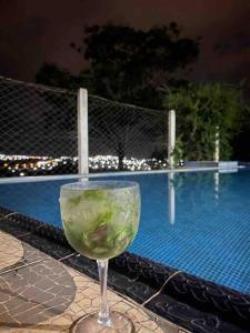 a glass of wine sitting on a table near a swimming pool at Recanto Minas a Goiás in Ceres