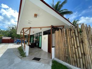 a house with a wooden fence next to it at Fins Pacific Coray Bay by Hiverooms in Samboan