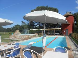 una piscina con sombrilla, mesas y sillas en Gästezimmer für 0 Personen 3 Kinder ca 30 qm in Pucciarelli, Trasimenischer See, en Pucciarelli