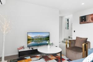een woonkamer met een tv en een bank en een tafel bij Stylish Cosy 2 Bed in Christchurch