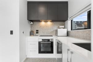 a white kitchen with black cabinets and a window at Stylish Cosy 2 Bed in Christchurch