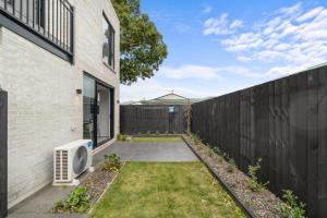 a backyard with a fence next to a house at Stylish Cosy 2 Bed in Christchurch