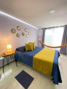 a bedroom with a blue and yellow bed and a table at Suite con hamaca y baño privado. in Manizales