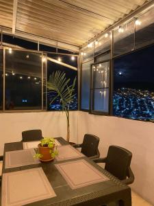 a dining room with a table and chairs and a view of the city at Suite con hamaca y baño privado. in Manizales