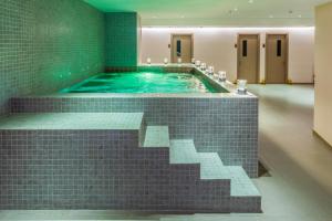a jacuzzi tub in a bathroom with green tiles at Awaken Da Nang Hotel in Danang