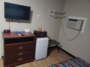 a room with a dresser with a television and a microwave at River Heights Motel in Crump