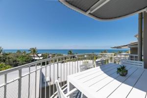 Un balcón con mesa y sillas y el mar. en 10 Andari, Sunshine Beach ~ Beachside Luxury Home, en Sunshine Beach