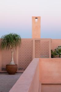a brick wall with two potted plants and a clock tower at Riad Dar Al Dall - This Time Tomorrow in Marrakech in Marrakesh