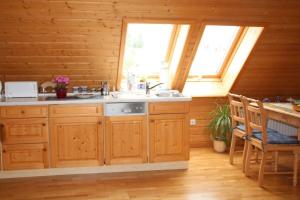 a kitchen with wooden cabinets and a sink and two windows at Große Ferienwohnung in Rauenstein mit Garten, Terrasse und Grill und Panoramablick in Rauenstein