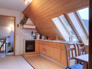 eine Küche im Dachgeschoss mit Holzschränken und Fenstern in der Unterkunft Große Ferienwohnung in Rauenstein mit Garten, Terrasse und Grill und Panoramablick in Rauenstein