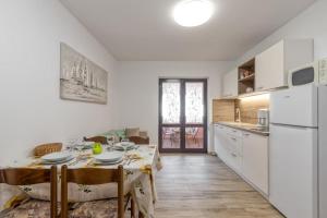 a kitchen with a dining table and a white refrigerator at Nettes Appartement in Rovinj mit Garten, Terrasse und Grill in Rovinj