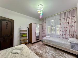 a bedroom with two beds and a window at Raduga West 'Pearl' Apartment in Koshkolʼ +21 photos