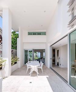 a white house with a table and chairs on a patio at The Platinum Luxury Villa ~ Walk to Beach, Village in Sunshine Beach