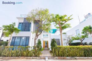 ein weißes Haus mit Bäumen davor in der Unterkunft WHITEDAY Villages ARIA SÁT BIỂN in Vũng Tàu