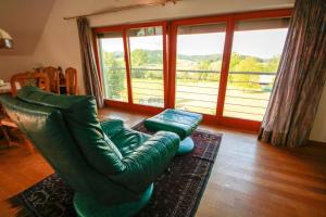 sala de estar con sofá de cuero verde y ventana grande en Unterkunft VILLA KATARINA, en Mokronog