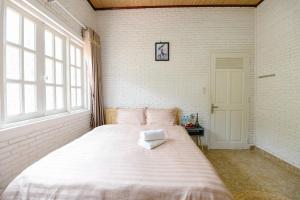 a large white bed in a room with windows at Scent Villa - Village in Da Lat
