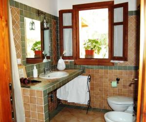 een badkamer met een wastafel en een toilet en 2 ramen bij Gästezimmer für 2 Personen 1 Kind ca 30 qm in Loiri Porto San Paolo, Sardinien Gallura - b58193 in Biacci