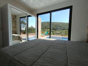 a bedroom with a large bed and large windows at Casa do Diospiro für 4 Personen Privatzimmer in São Bartolomeu de Messines +9 photos